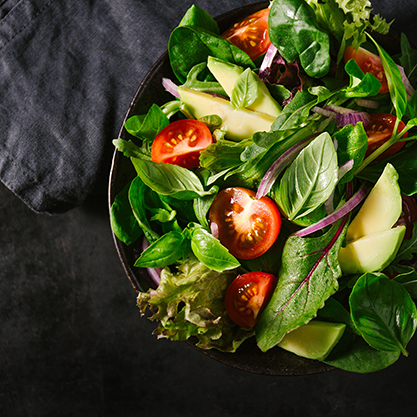 A rustic bowl of bright green lettuce and baby spinach, topped with cherry tomatoes.